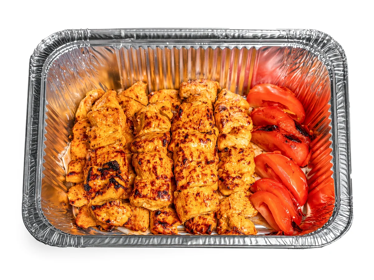 Joojeh family platter: rows of grilled saffron chicken kababs with grilled tomatoes in a large foil tray at AFRA Grill, Saskatoon