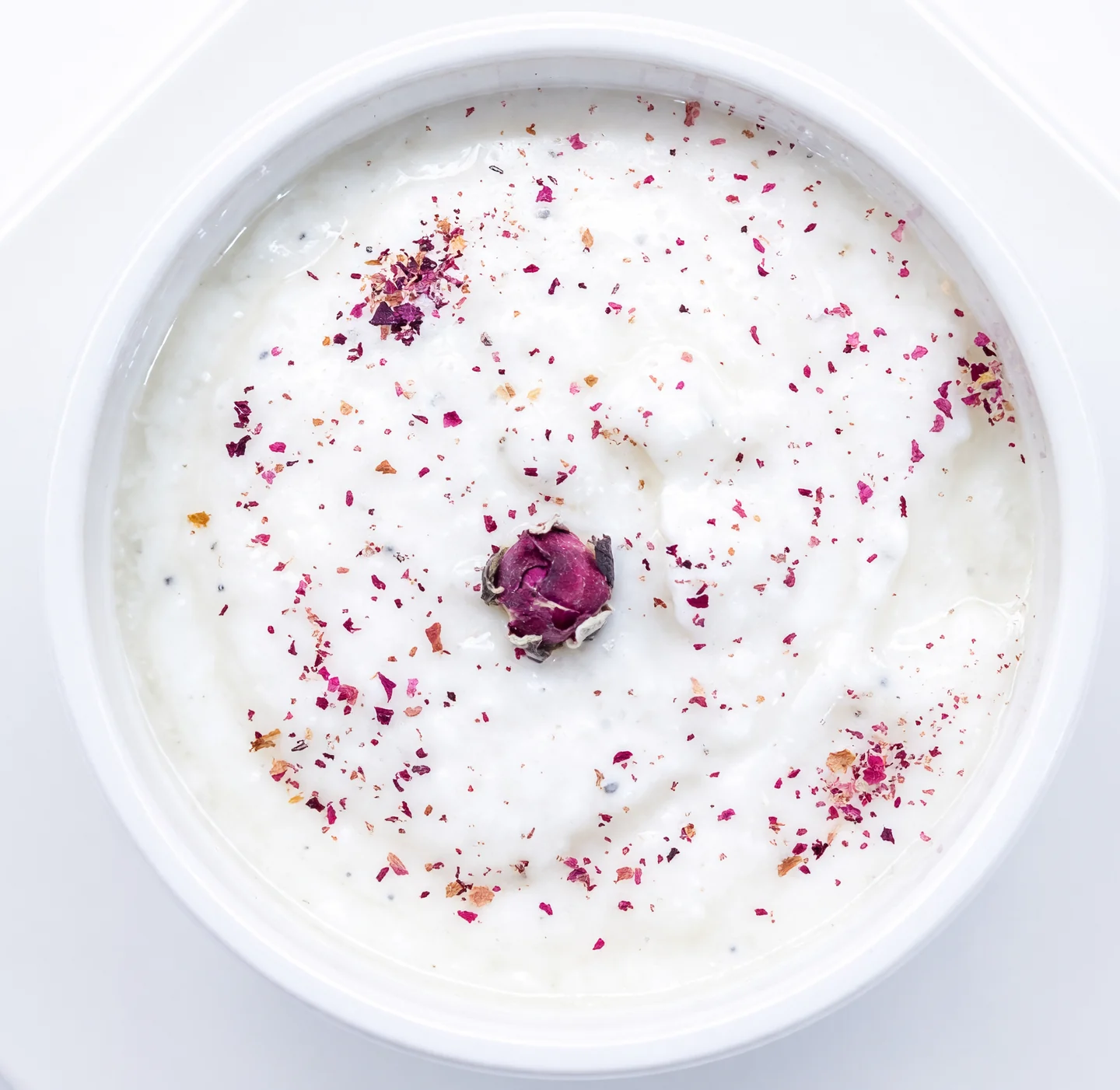 Maust moosir shallot yogurt dip dusted with sumac and a dried rosebud in a white bowl at AFRA Grill, Saskatoon