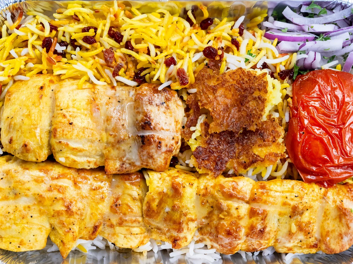 Joojeh: two skewers of saffron-marinated grilled chicken with saffron rice, tahdig and a grilled tomato in a foil tray at AFRA Grill, Saskatoon