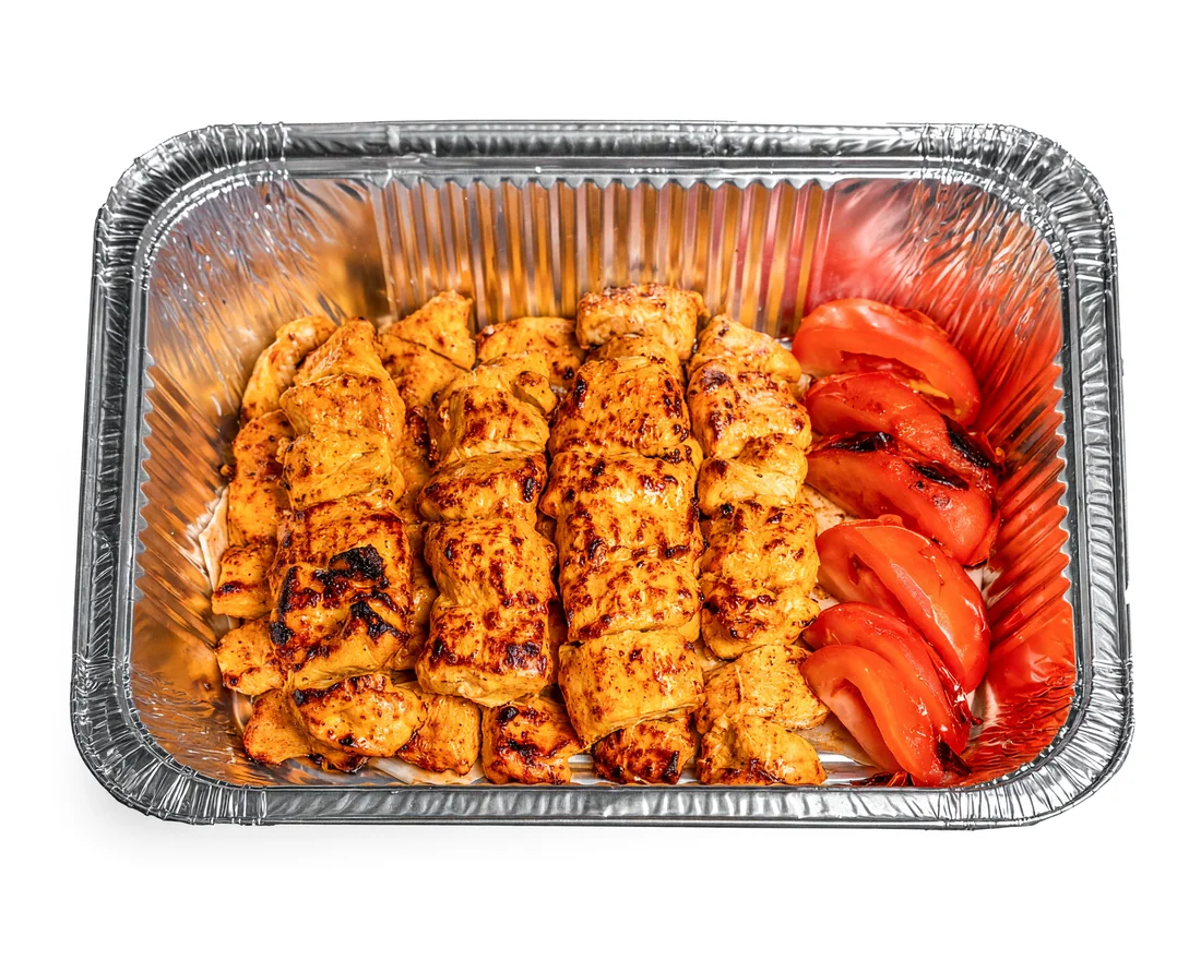 Joojeh family platter: rows of grilled saffron chicken kababs with grilled tomatoes in a large foil tray at AFRA Grill, Saskatoon