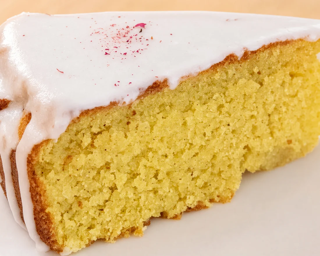 A slice of Persian love cake with white glaze and a sprinkle of dried rose petals at AFRA Grill, Saskatoon